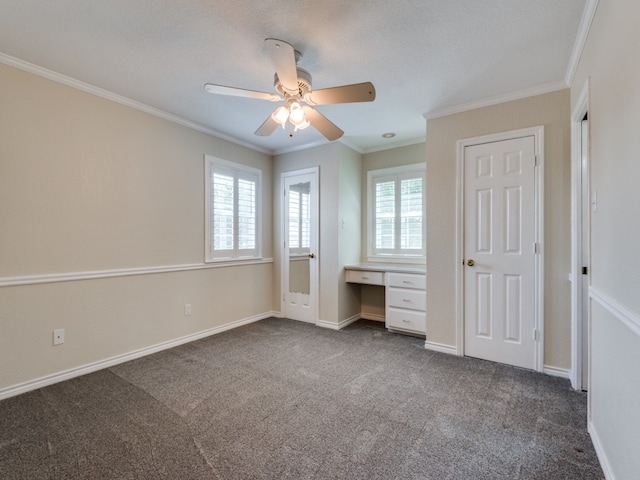 unfurnished bedroom with ornamental molding, built in study area, baseboards, and dark colored carpet