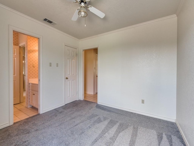 spare room with visible vents, light colored carpet, a ceiling fan, and ornamental molding