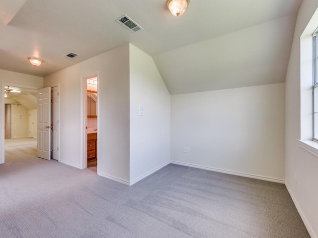 bonus room with vaulted ceiling, light colored carpet, visible vents, and baseboards