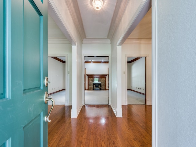 entryway with a glass covered fireplace, crown molding, wood finished floors, and baseboards