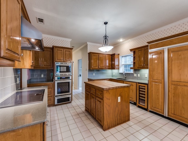 kitchen with a sink, stainless steel appliances, butcher block countertops, and wallpapered walls