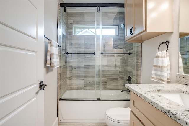 full bathroom with vanity, shower / bath combination with glass door, and toilet