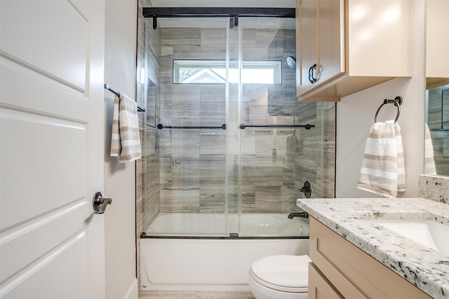 full bathroom with enclosed tub / shower combo, vanity, and toilet