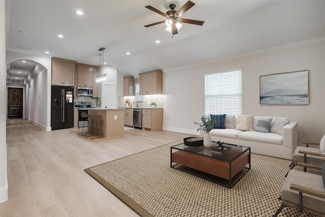 living room featuring sink, crown molding, light wood-type flooring, and ceiling fan