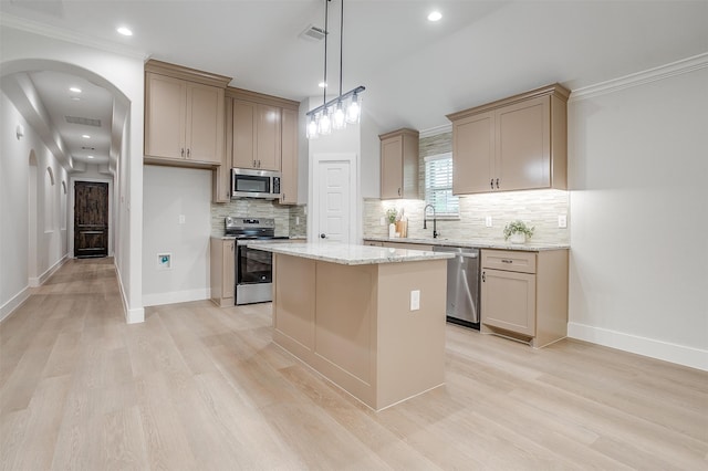 kitchen featuring decorative backsplash, stainless steel appliances, light hardwood / wood-style flooring, and a center island