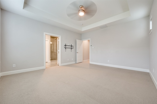 unfurnished bedroom featuring a raised ceiling and light carpet