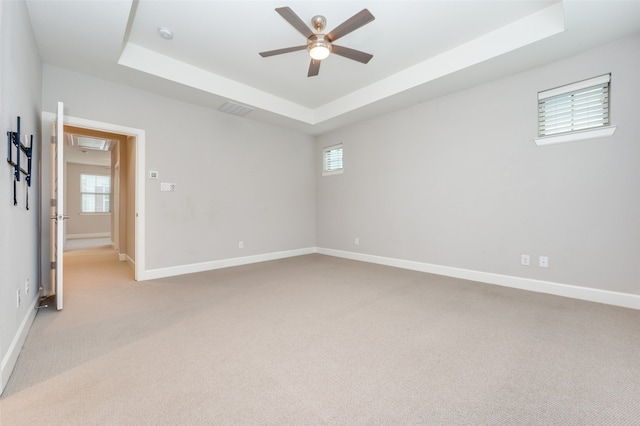 carpeted spare room featuring ceiling fan and a tray ceiling