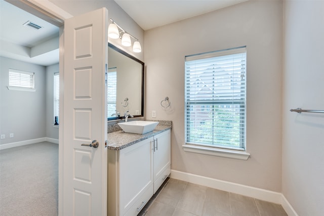 bathroom with tile patterned floors, vanity, and a healthy amount of sunlight