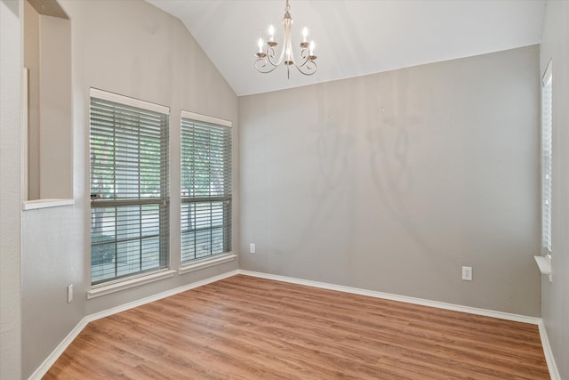 spare room featuring lofted ceiling, a notable chandelier, and hardwood / wood-style floors