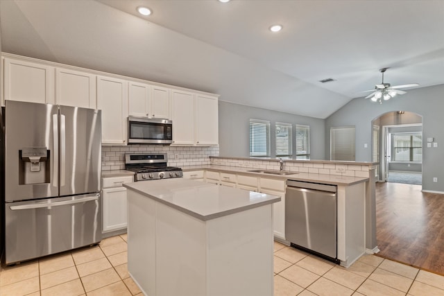 kitchen featuring light hardwood / wood-style flooring, stainless steel appliances, sink, kitchen peninsula, and a center island