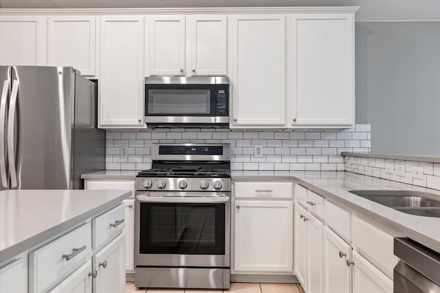 kitchen featuring light tile patterned floors, white cabinets, backsplash, and stainless steel appliances