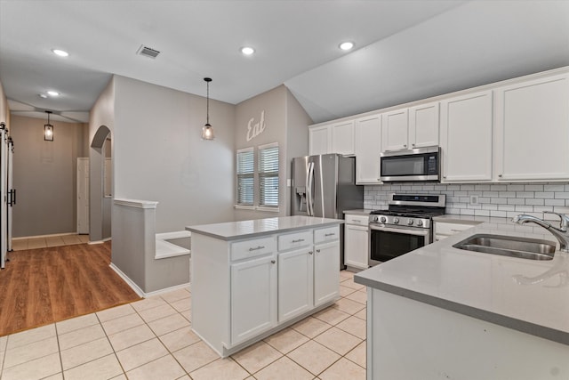 kitchen with white cabinetry, light hardwood / wood-style flooring, stainless steel appliances, hanging light fixtures, and sink