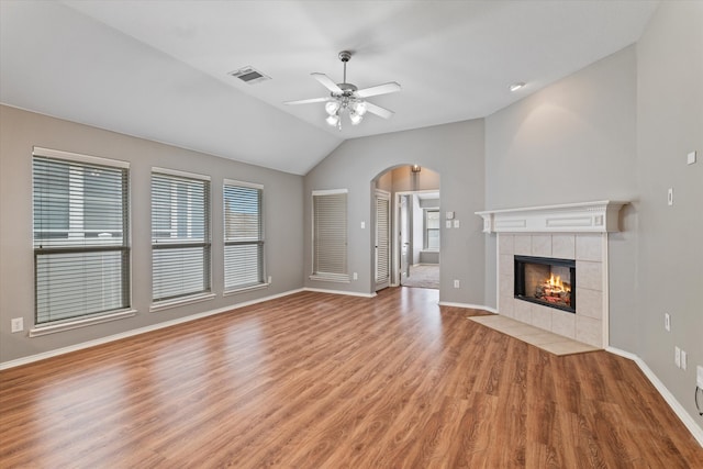 unfurnished living room with light hardwood / wood-style floors, a tiled fireplace, vaulted ceiling, and ceiling fan