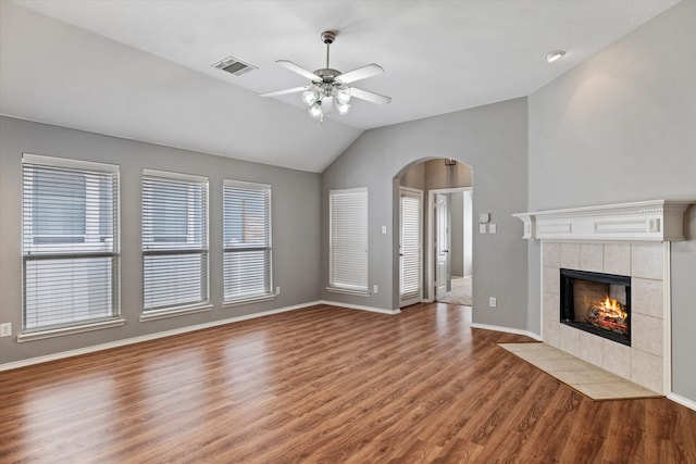 unfurnished living room featuring lofted ceiling, a tile fireplace, hardwood / wood-style floors, and ceiling fan