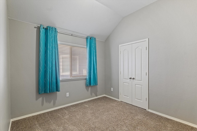 unfurnished bedroom with carpet, a closet, and vaulted ceiling