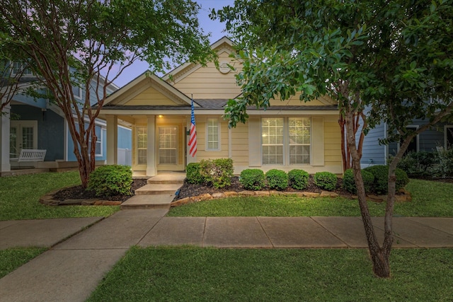 bungalow-style home featuring covered porch and a lawn