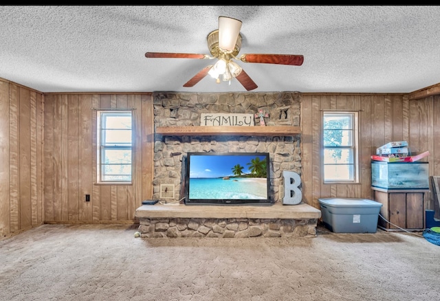 unfurnished living room with carpet, a textured ceiling, a stone fireplace, and wood walls