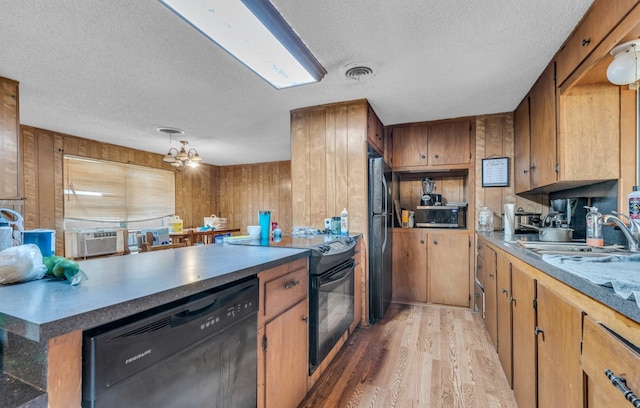 kitchen featuring wood walls, sink, black appliances, and a notable chandelier