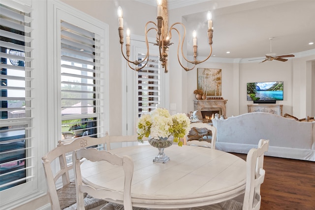 dining area with a fireplace, dark hardwood / wood-style floors, crown molding, and ceiling fan with notable chandelier