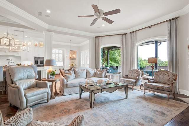 living room with ornate columns, wood-type flooring, crown molding, and ceiling fan