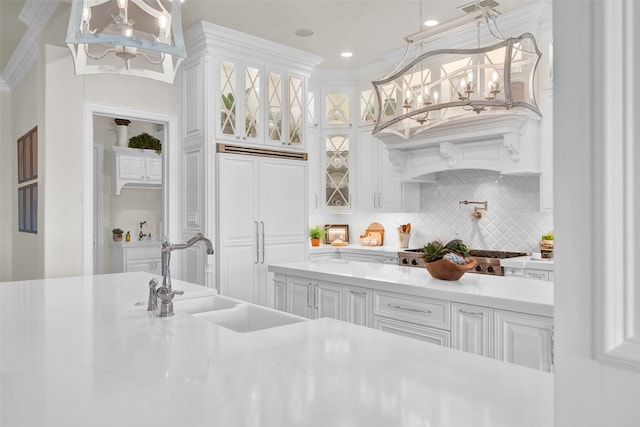 bar with white cabinetry, decorative backsplash, crown molding, sink, and paneled refrigerator