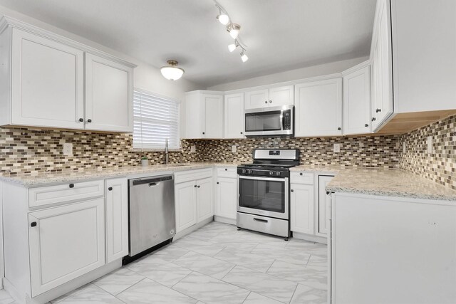 kitchen with white cabinets, sink, decorative backsplash, appliances with stainless steel finishes, and light stone counters