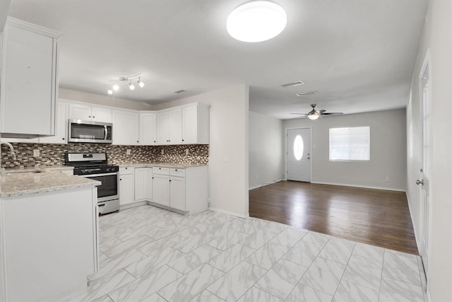 kitchen with light stone counters, sink, white cabinets, and stainless steel appliances