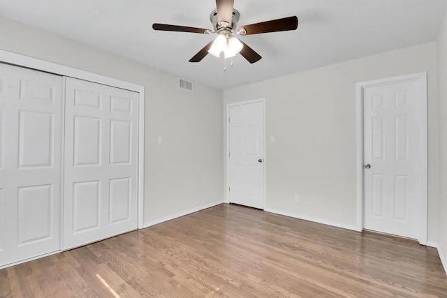 unfurnished bedroom featuring hardwood / wood-style flooring, ceiling fan, and a closet