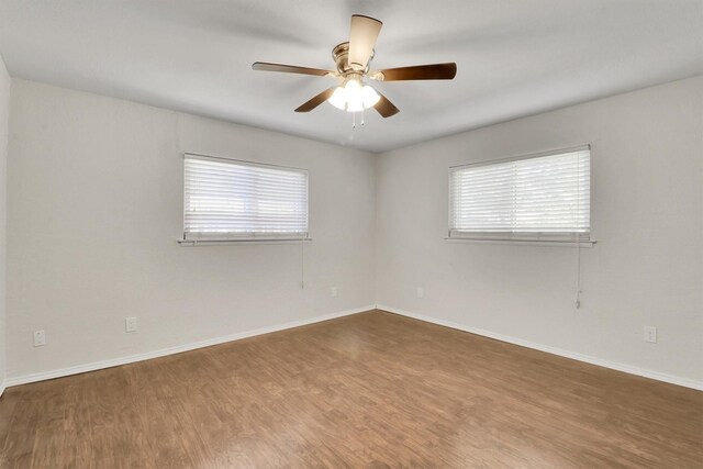 empty room with a wealth of natural light, ceiling fan, and hardwood / wood-style flooring