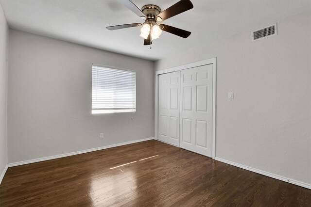 unfurnished bedroom featuring ceiling fan, a closet, and dark wood-type flooring