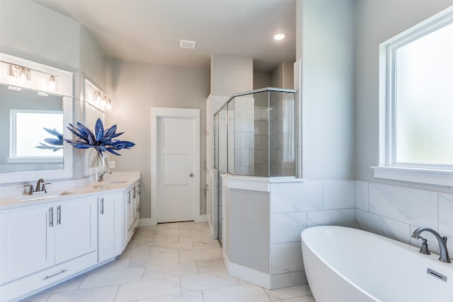 bathroom with plenty of natural light, independent shower and bath, dual bowl vanity, and tile patterned floors