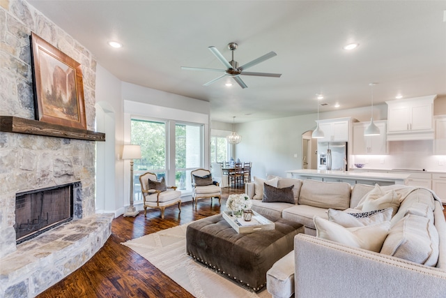 living room with dark wood-type flooring, a fireplace, and ceiling fan