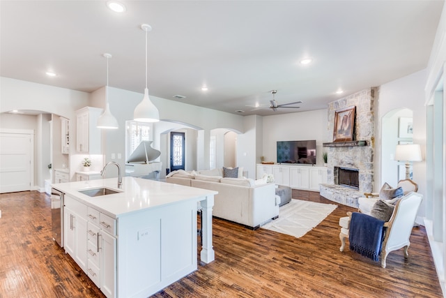 kitchen with a fireplace, sink, wood-type flooring, and a kitchen island with sink