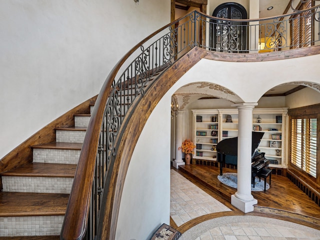 2115 Paradise Ranch Trl, Mckinney, TX 75071 - staircase with arched walkways, wood finished floors, a high ceiling, and ornate columns