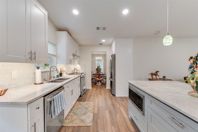 kitchen with sink, decorative light fixtures, light hardwood / wood-style flooring, appliances with stainless steel finishes, and white cabinets