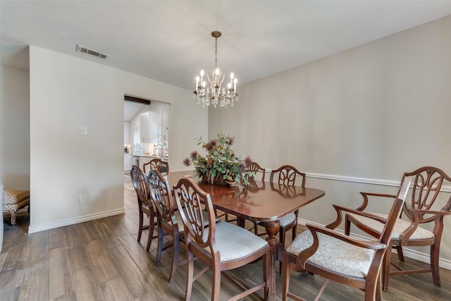 dining room with wood-type flooring and an inviting chandelier