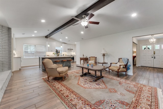 living room with vaulted ceiling with beams, ceiling fan with notable chandelier, and light hardwood / wood-style flooring