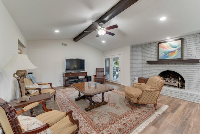 living room featuring a brick fireplace, light hardwood / wood-style flooring, lofted ceiling with beams, and ceiling fan