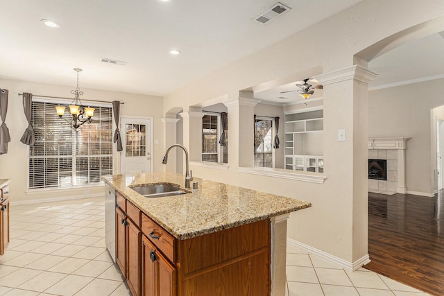 kitchen with visible vents, brown cabinets, a sink, light tile patterned floors, and decorative columns