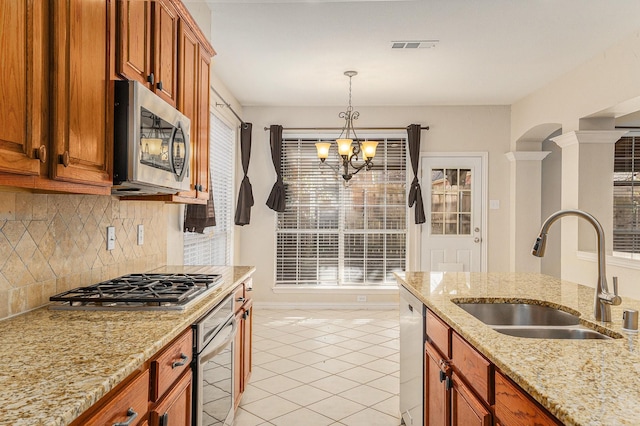 kitchen featuring pendant lighting, appliances with stainless steel finishes, sink, light tile patterned floors, and light stone countertops