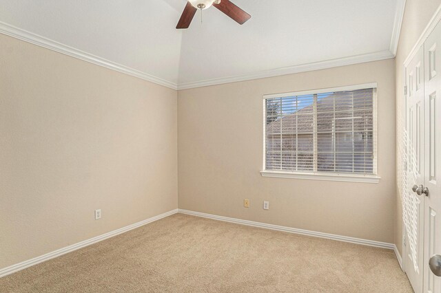 carpeted spare room featuring vaulted ceiling, baseboards, ceiling fan, and ornamental molding