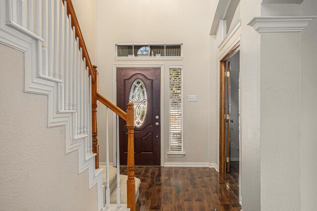 entrance foyer featuring dark wood-type flooring, a notable chandelier, and a towering ceiling