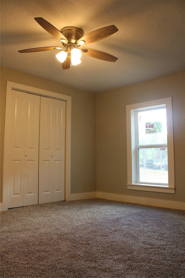 unfurnished bedroom with a textured ceiling, carpet flooring, ceiling fan, and a closet