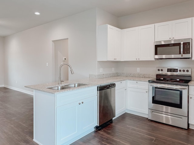 kitchen with sink, white cabinetry, stainless steel appliances, light stone counters, and kitchen peninsula