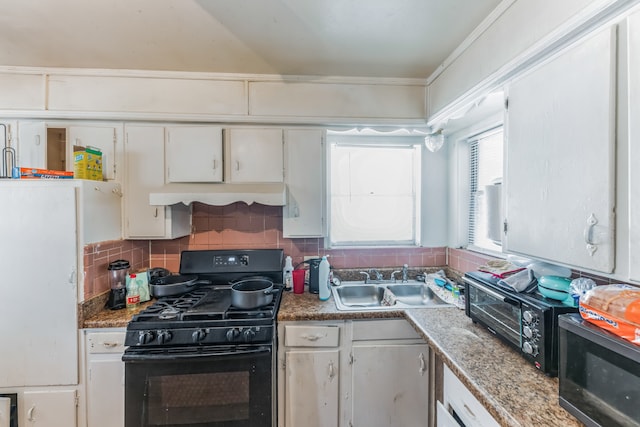 kitchen featuring black range with gas stovetop, white cabinets, premium range hood, decorative backsplash, and sink