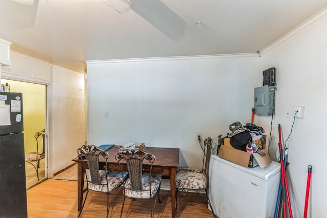 dining space with crown molding, electric panel, and light hardwood / wood-style flooring