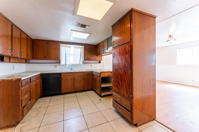 kitchen featuring backsplash, visible vents, black dishwasher, and brown cabinetry