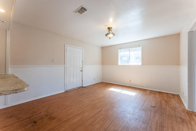 empty room with visible vents, baseboards, and wood finished floors