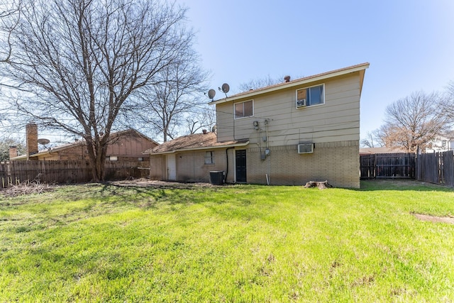 back of house featuring a yard, brick siding, a fenced backyard, and a wall mounted AC