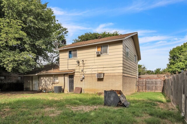 back of house featuring an AC wall unit, central air condition unit, and a yard